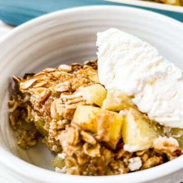 A close up picture of some apple baked oatmeal topped with coolwhip.