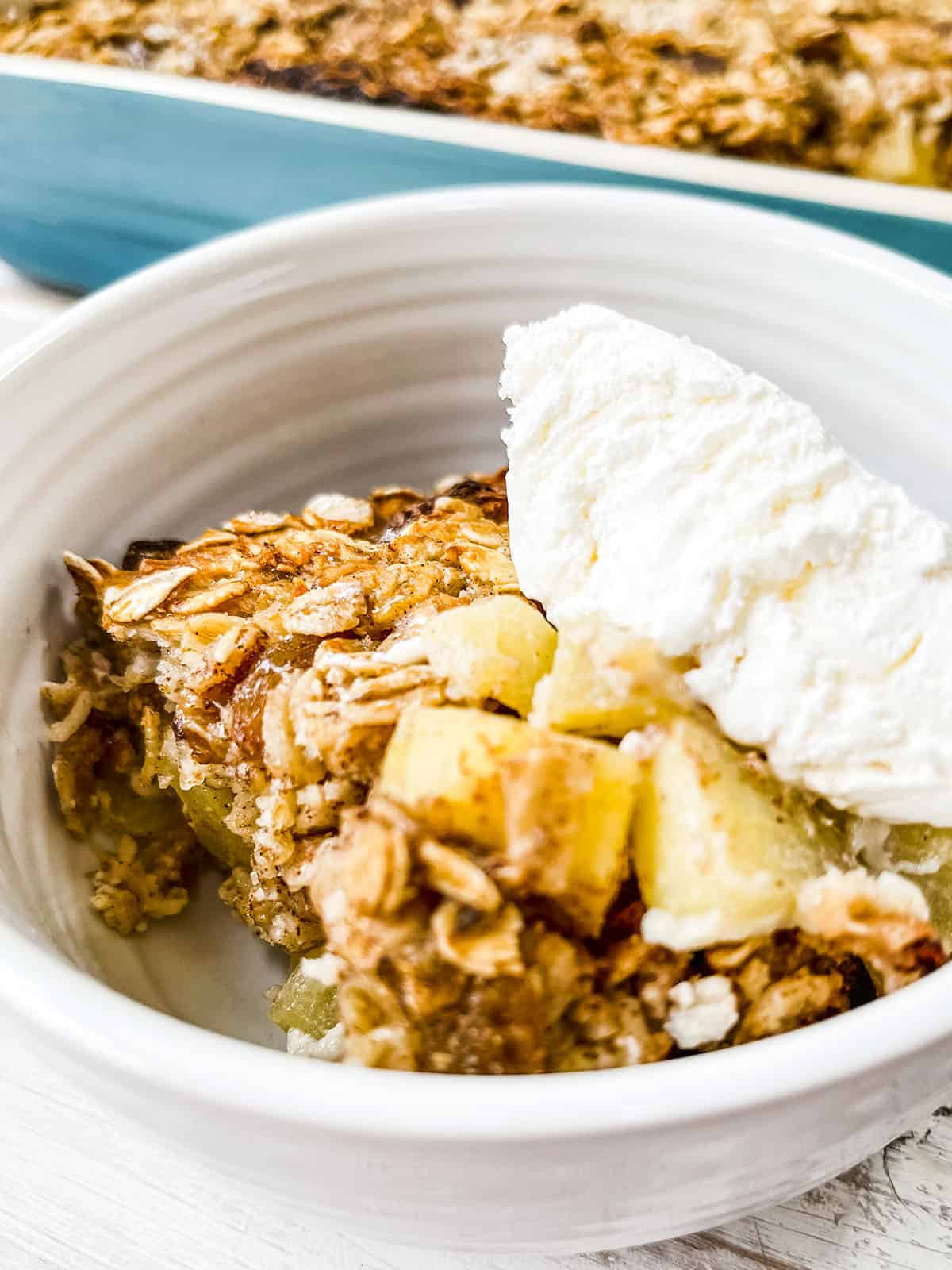 A close up picture of some apple baked oatmeal topped with coolwhip. 
