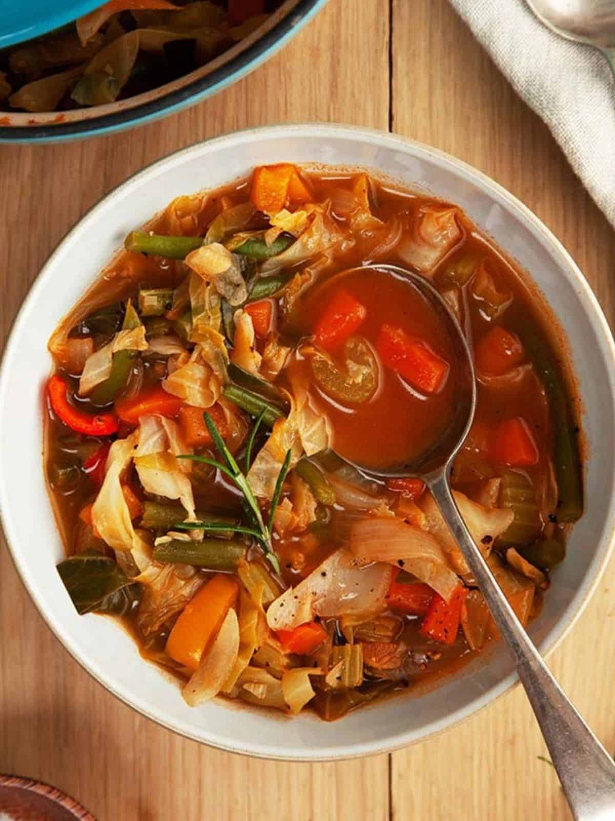 A bowl of soup with a spoon on a wooden table.