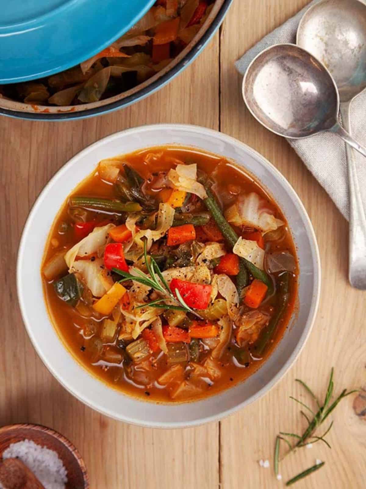 A bowl of low calorie cabbage soup on a wooden table. 