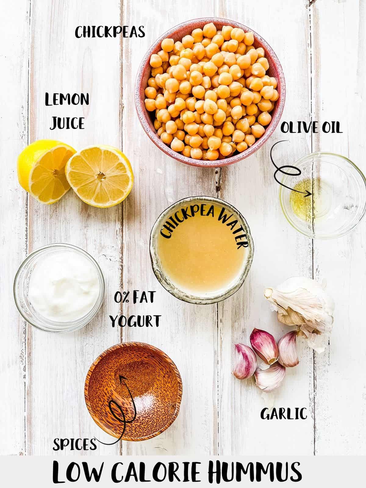The ingredients needed to make hummus in dishes on a white wooden table.