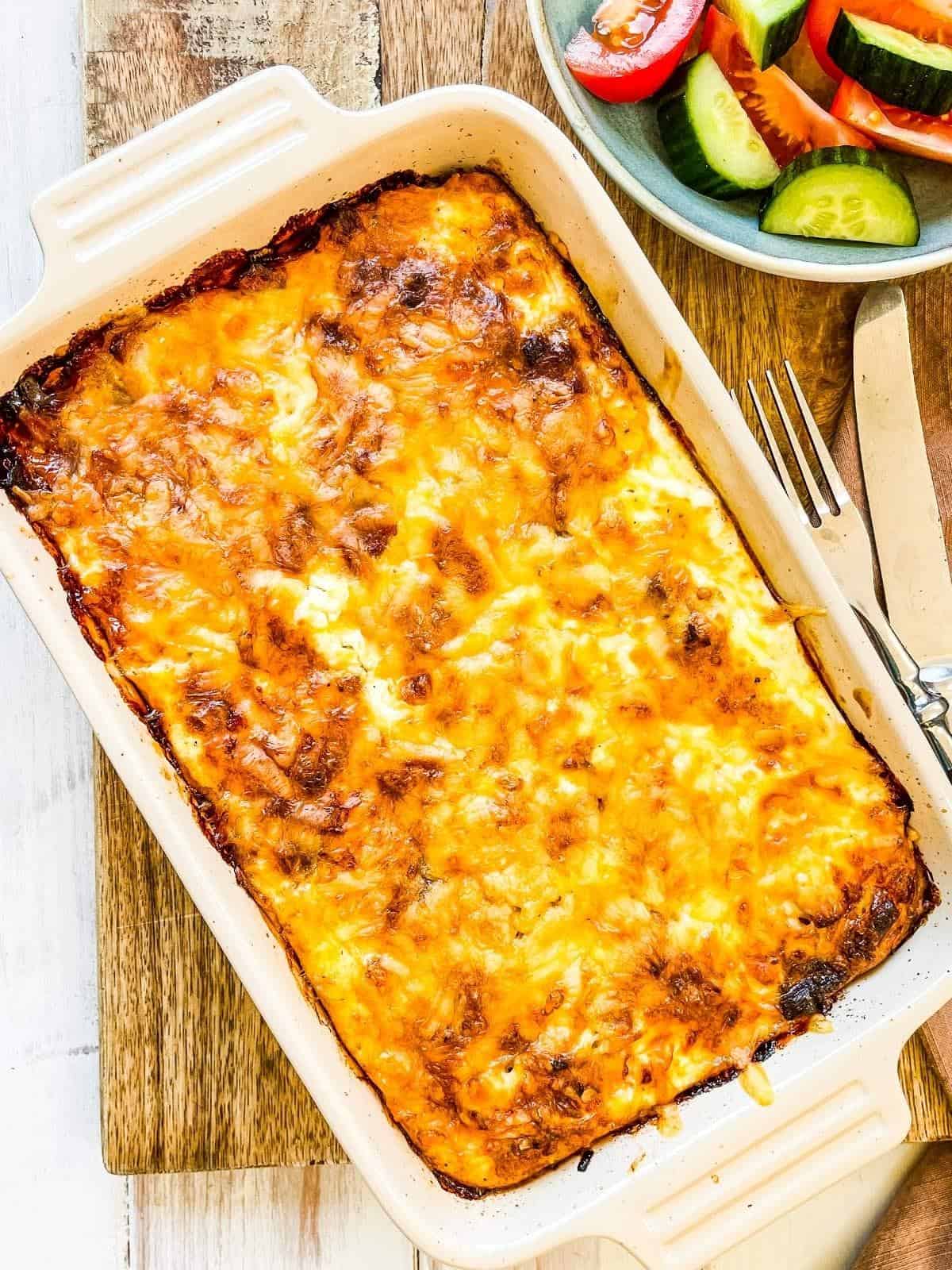 A casserole dish full of low calorie breakfast casserole on a wooden board.