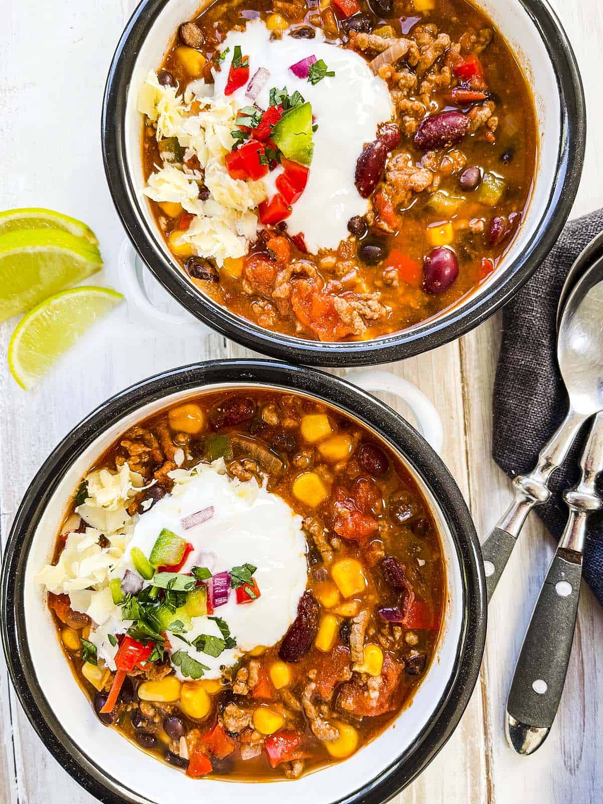 Two bowls of low calorie taco soup on a white table.