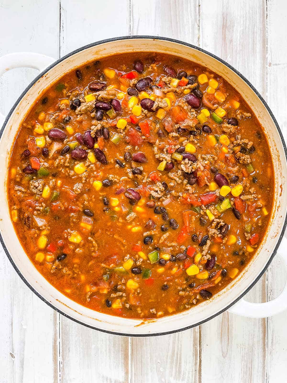 A skillet full of taco soup on a wooden table.